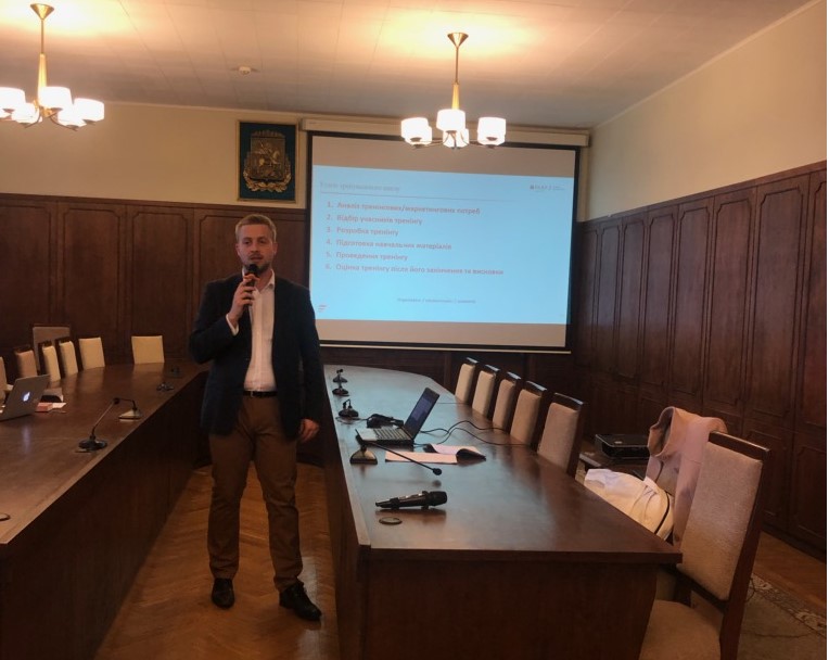 Młody mężczyzna stoi na sali przy stole konferencyjnym