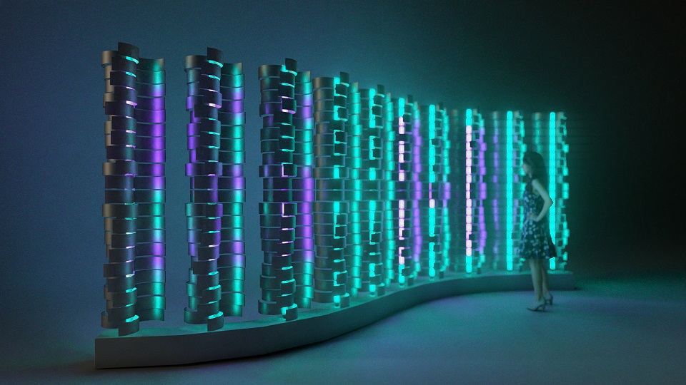 Zdjęcie przedstawia instalację interaktywną, na którą składa się rząd kolumn złożonych z modułów o nieregularnych kształtach, stojących na podstawie w kształcie litery „s”. Części wybranych kolumn świecą się na różne kolory – biały, zielony oraz fioletowy. Instalacja stoi w ciemnym pomieszczeniu i przygląda się jej kobieta. 