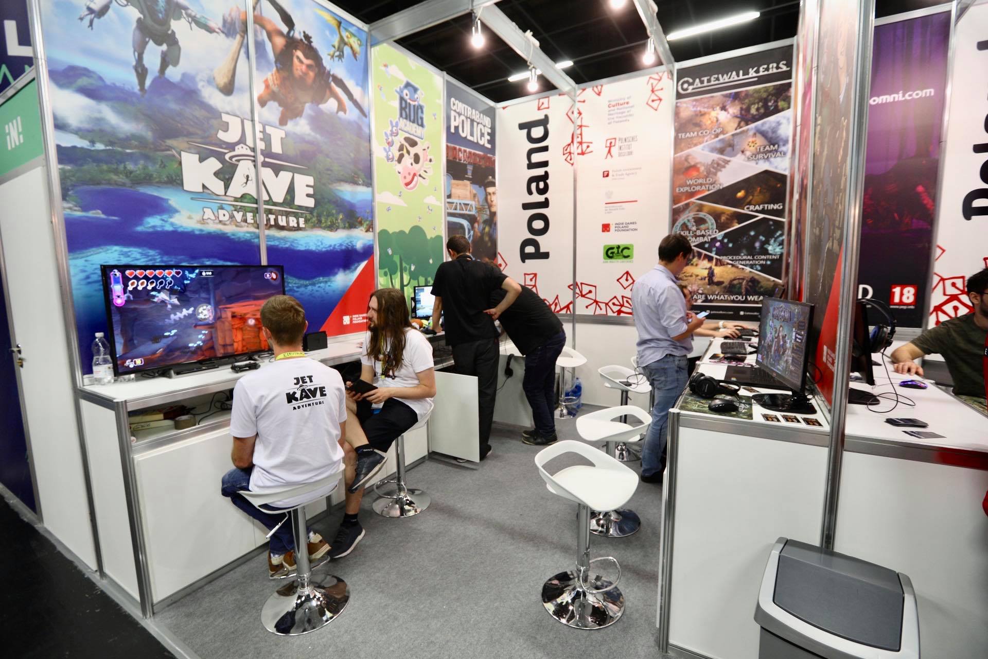 Ludzie przy trzech stanowiskach z komputerami (przy każdym po dwie osoby i rozmawiają ze sobą pokazując jednocześnie coś na monitorach)