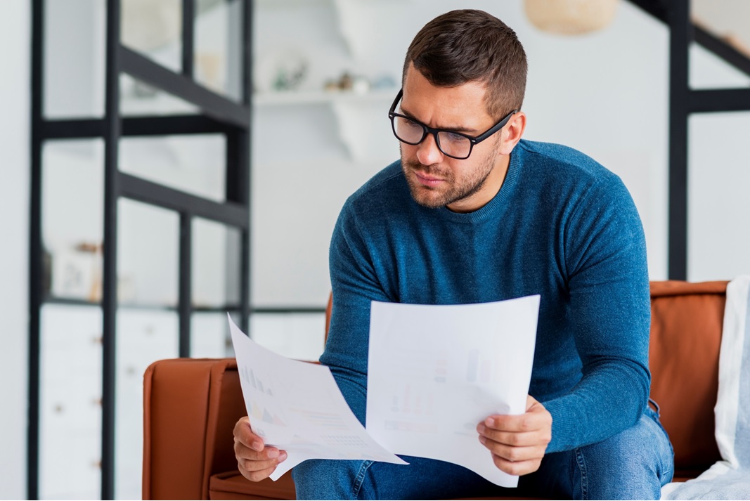 młody mężczyzna w okularach siedzi na kanapie i przegląda dokumentację